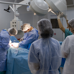 A medical team of 5 people in theatre, two of them operating on a patient